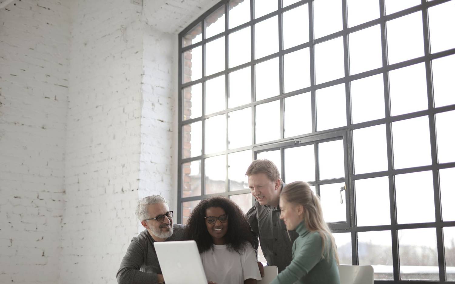 A small team in conversation beside tall windows