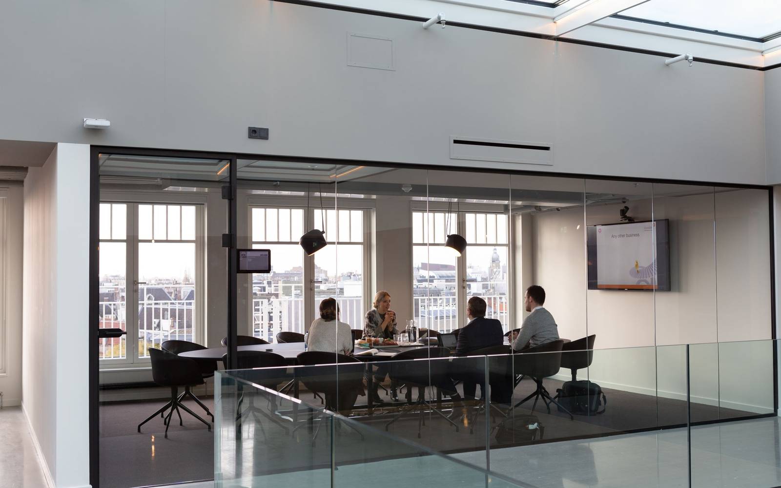 A glass-walled meeting room with a discussion in progress