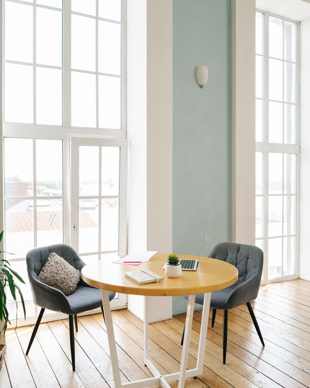 A bright loft workspace with tall arched windows and a small team at work